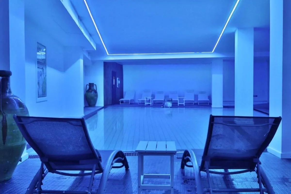 Area relax della spa con lettini e piscina interna illuminata di blu