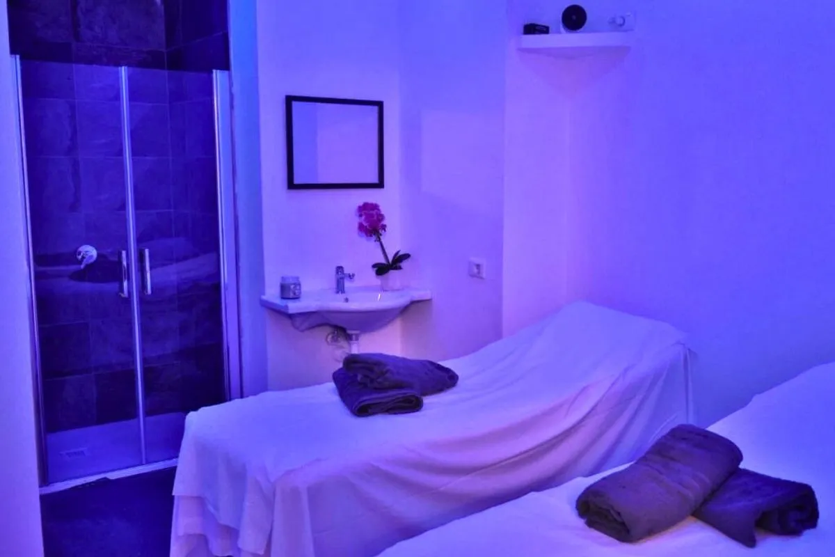Sala massaggi della spa con lettino, illuminazione viola e doccia