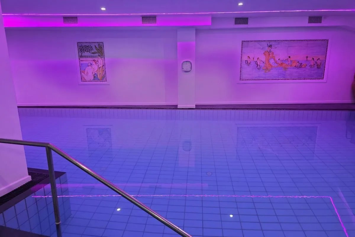 Piscina interna con illuminazione viola e decorazioni a parete