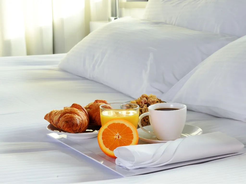 Colazione a letto con cornetti, succo d'arancia e caffè su vassoio bianco