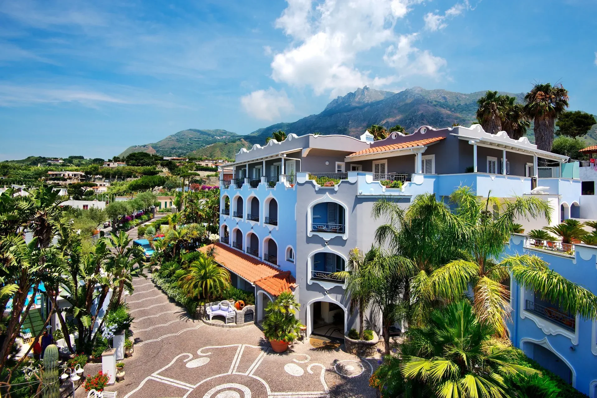 Vista esterna dell'edificio del resort circondato da palme con la montagna sullo sfondo