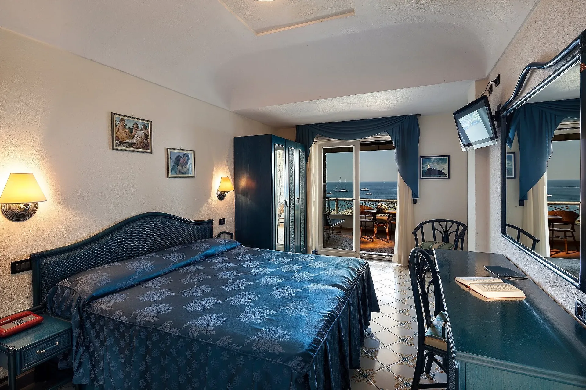 Camera matrimoniale elegante in blu con balcone panoramico affacciato sul mare