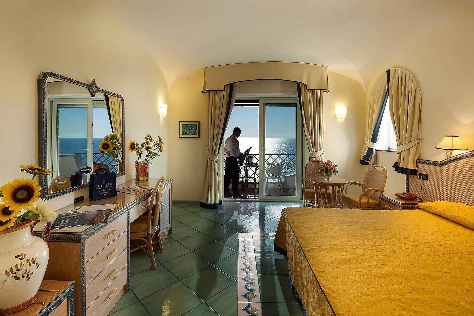 Camera matrimoniale con balcone affacciato sul mare e arredi in tonalità gialle