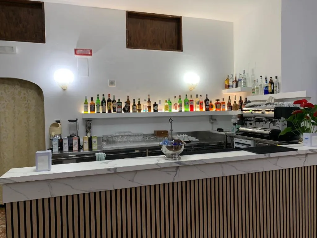 Bancone bar in marmo con macchina del caffè e ampia selezione di bottiglie di liquori