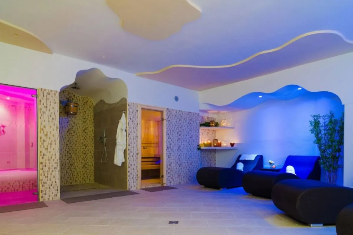 Area benessere della spa con lettini relax, sauna, bagno turco e illuminazione soffusa colorata