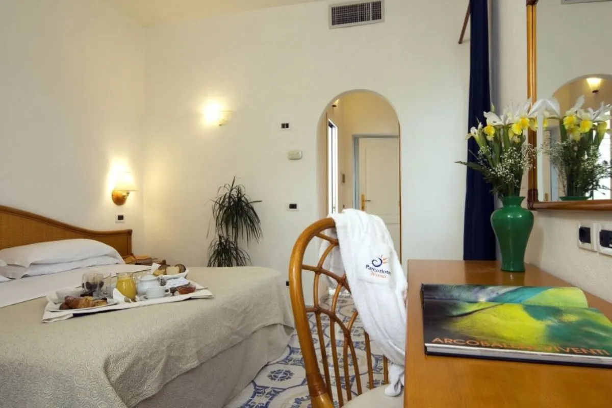 Camera con letto matrimoniale, vassoio colazione, scrittoio in legno e specchio con fiori